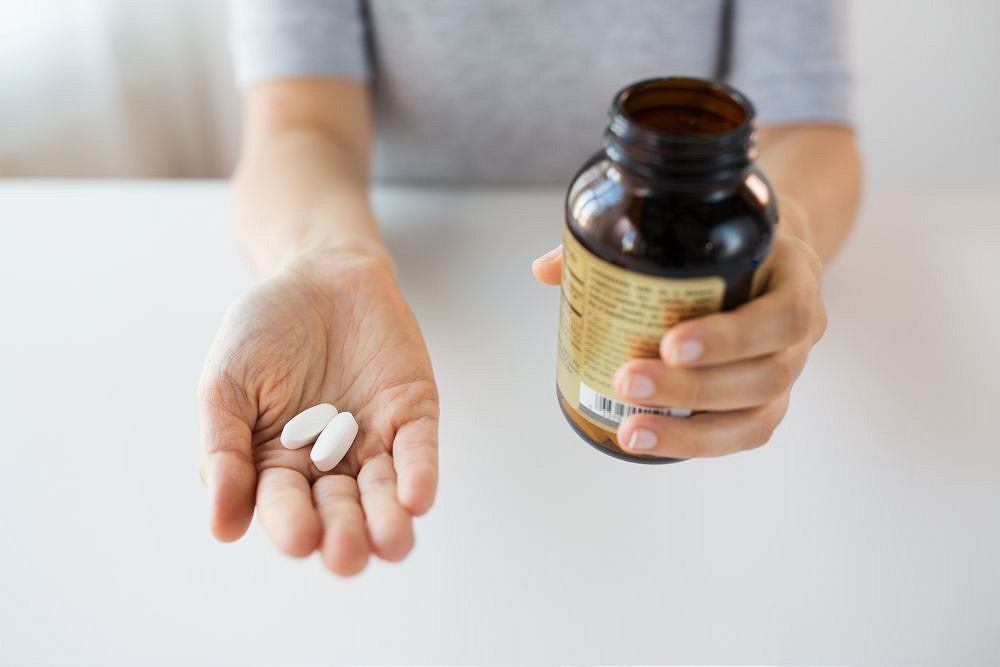 close up of hands holding medicine pills and jar